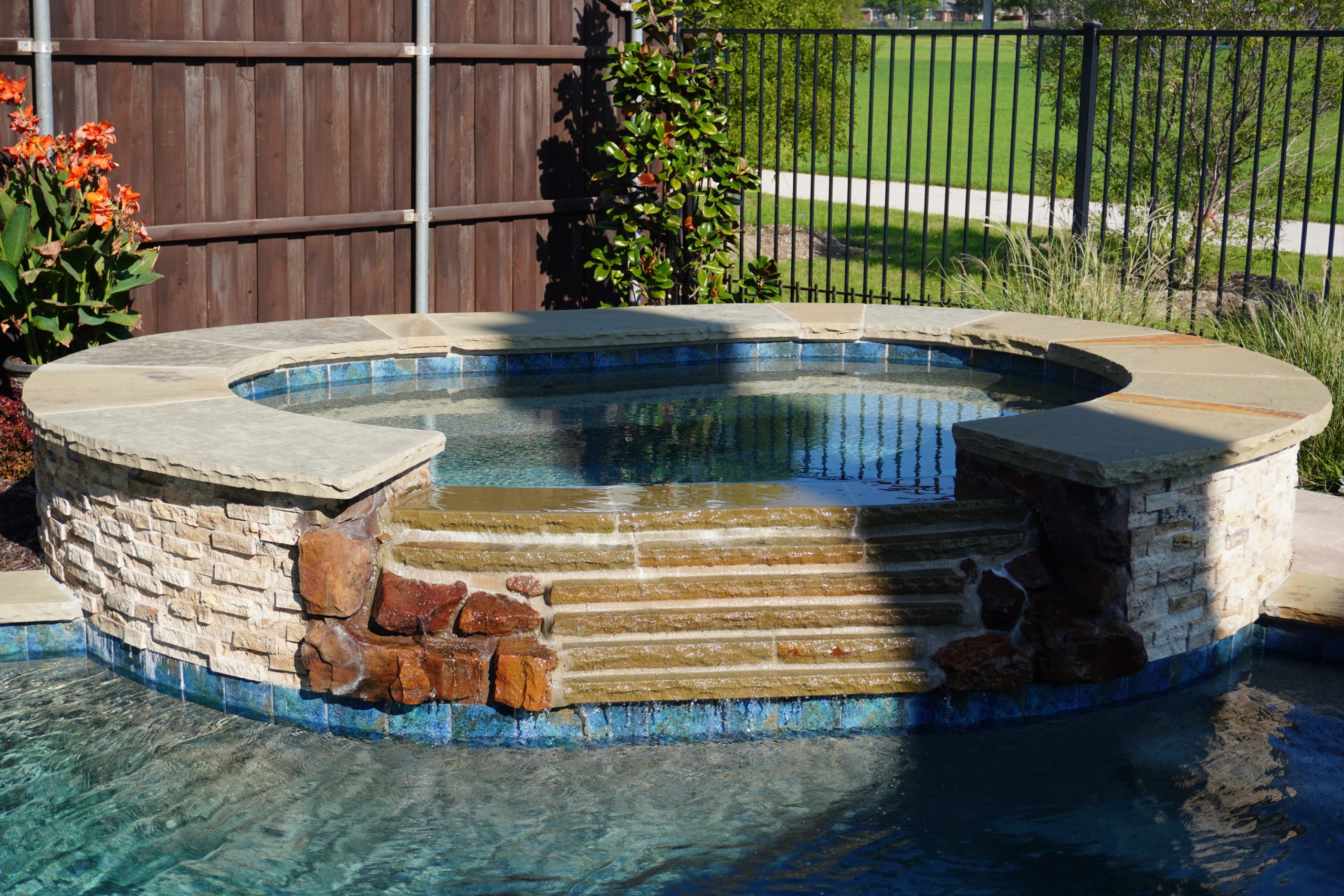 Raised stone spa with a tiered spillover into the pool, built by Hobert Pools & Spas